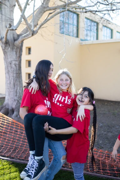 2 girls caring another girl in their arms